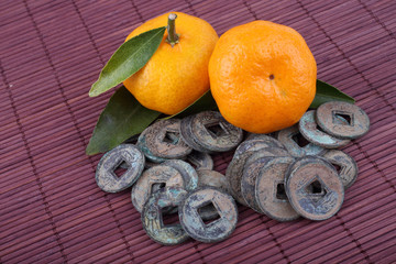 Mandarin oranges and ancient Chinese coins on bamboo background. Symbols of luck and Chinese New Year.