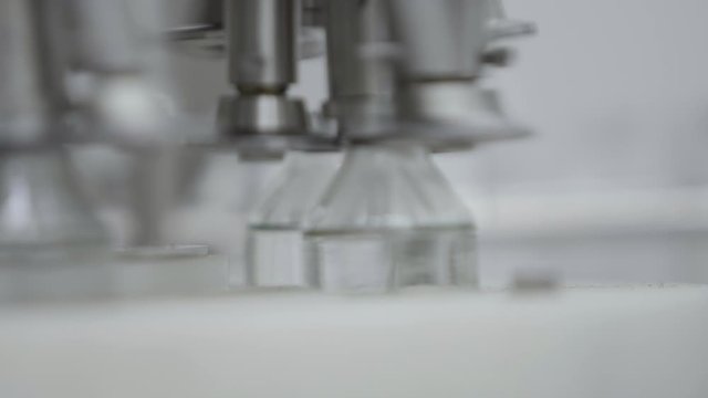 glass bottles filled and sealed with rubber caps on a medical solution conveyor line aluminium cap packaging section close up medical industry
