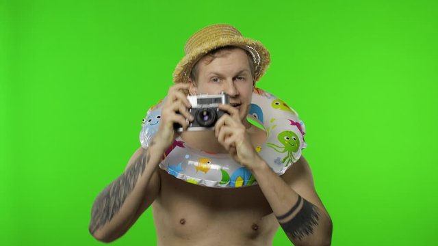 Shirtless man tourist photographer is taking photos on retro camera. Chroma key