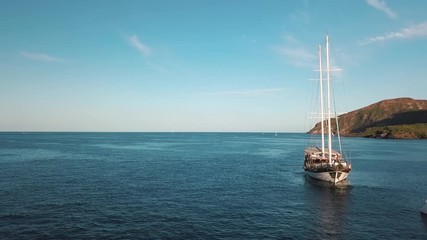 Aerial view on sailing boat with people on board near Lipari Islands, Sicily, Italy. Mediterranean sea, mountains and blue sky