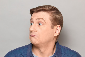 Obraz premium Portrait of blond mature man with silly perplexed expression on face