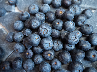 a bunch of large blueberries on a stone blue background close up