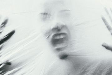 Beautiful female face through the fabric. Scary black and white background