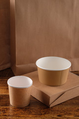 Street fast food paper cups, plates and containers. Eco-friendly food packaging on wooden background. Carering of nature and recycling concept.