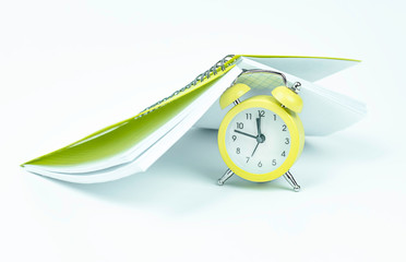 Alarm clock and open notebook on white background