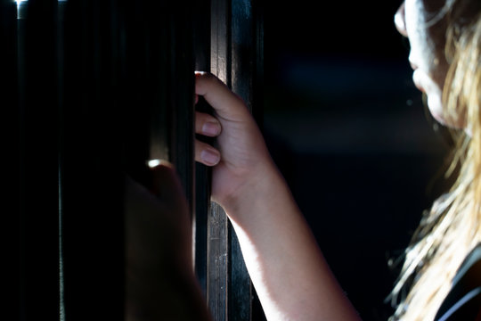 Abstract woman's hand catches the iron fence in the dark and the light survives.