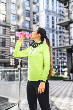 Restore water balance. A young girl in a sports outfit drinks water from a sports bottle, quenches thirst during sports Vertical photo