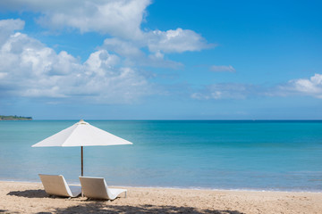 tropical beach with umbrella and two chairs