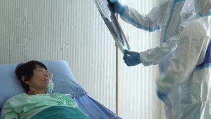 doctor and nurse in personal protective equipment or ppe looking at chest x-ray of the patient who infected with covid-19 or coronavirus in hospital. medical concept - Powered by Adobe