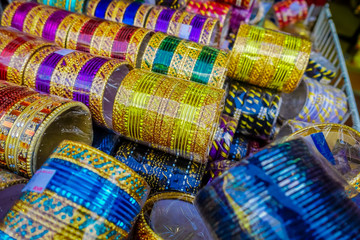 Fototapeta na wymiar Colourful Indian wrist bracelets stacked in piles on display at a shop in Little India in Singapore. Colorful urban concept
