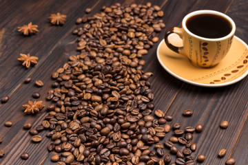 Coffee beans scattered on table and star anise. Cup of coffee.