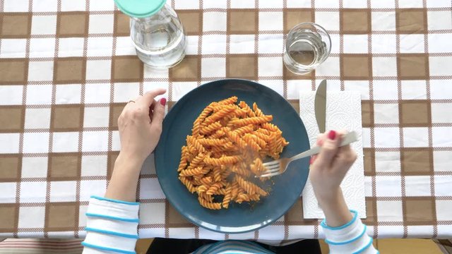 Woman eating fresh pasta with fork, from above