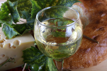 Wine, grape, cheese and bread on table.