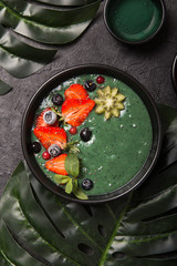 Colorful, healthy food. Acai smoothie bowl. Keto breakfast idea. Fruit curd smoothie, acai. Breakfast with green spirulina, strawberry, chia, kiwi in black plate