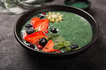 Colorful, healthy food. Acai smoothie bowl. Keto breakfast idea. Fruit curd smoothie, acai. Breakfast with green spirulina, strawberry, chia, kiwi in black plate