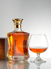 close up view of bottle of whiskey and a glass aside on grey back. 