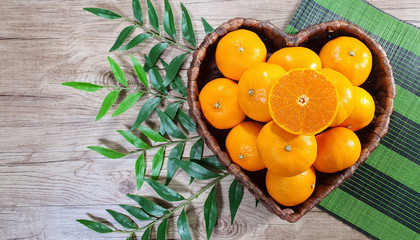 tangerines in heart shaped basket and green leaves