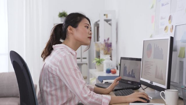 taiwanese female manager analyzing financial performance of company on computer and marking down briefly on paper. portrait of asian lady working from home studio.