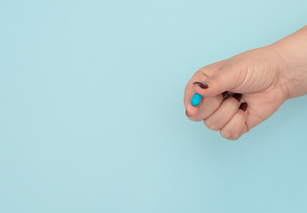 Blue pill on female hand on blue background. Seasonal diseases. Right choice, medicine concept. Flat lay style with copy space, top view.