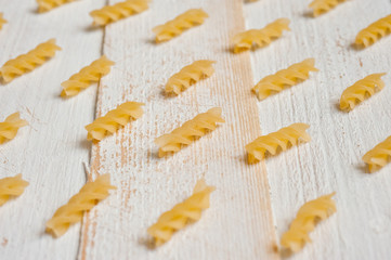 Fototapeta na wymiar Spiral pasta on a white wooden background. Background for cooking and food.