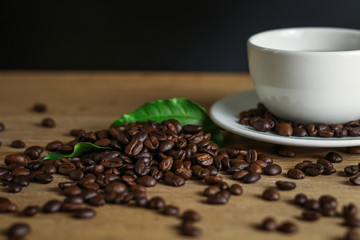 White coffee cup and coffee beans on wooden table with copyspace for text. Selective focus.
