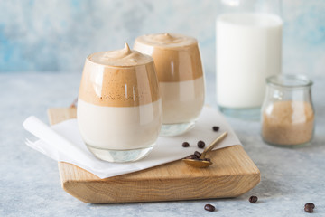  Dalgona Frothy Coffee is a South Korean drink with whipped instant coffee, sugar and milk, on light  concrete table