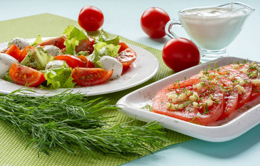 Italian Caprese salad with sliced tomatoes, mozzarella cheese, lettuce leaves, olive oil on a plate. Still-life.