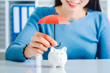 Young asian woman hand hold umbrella toy to protect the home and money for saving money and house...