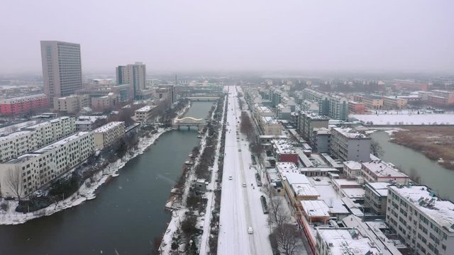 Linear shot of a road along a moat on a snowy winter day in China. Snowflakes