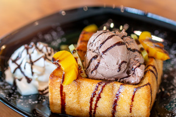 Toasted bread and chocolate ice cream with fruits topping. Chocolate  Ice cream with toasted bread on plate. Ice cream with toasted and chocolate topping in Coffee shop.