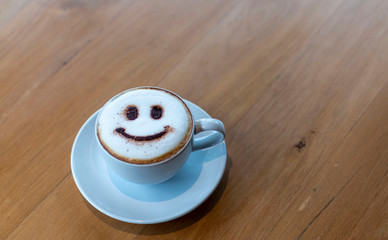 Cappuccino is an espresso-based coffee drink. Latte art at cafe. White Cup of art latte on a cappuccino coffee. Cappuccino with smiley frothy foam, coffee cup top view closeup. 