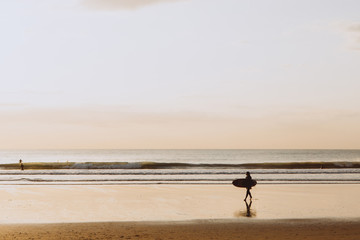 Fototapeta na wymiar Ocean sunset, surfer backlit silhouette, warm orange colour