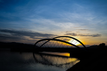 Fototapeta na wymiar Beautiful sunrise with silhouette of a bridge and lake at Putrajaya, Malaysia 