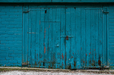 blue wooden door. Garage gates closed by retro padlock. Architectural backdrop