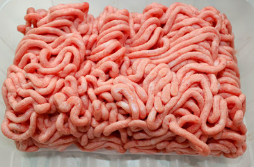 Ground meat ground in a meat grinder on a light background.