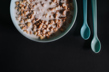Blue bowl with musli and milk and two little blue spoons on grey background as a healthy breakfast