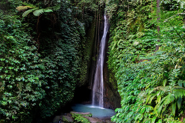 A waterfall falls beside a dark cave, pooling in a clear waterfall vault
