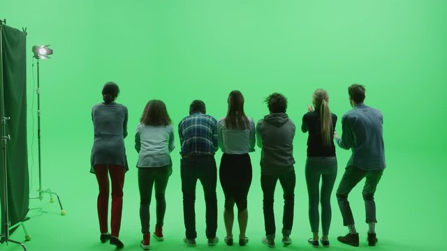 Green Screen Chroma Key Studio: Row of Seven People / Fans Cheering, Screaming, Jumping, Clapping and Applauding at the Public Sport Event, Concert, Festival, Party. Back View Full Shot. Slow Motion