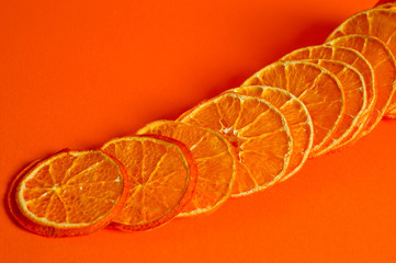 Chips of dried tangerines, sliced in thin circles. Shot on an orange background. Background for vegetarianism and healthy eating.