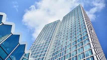 Fototapeta premium Structural glass wall reflecting blue sky. Abstract modern architecture fragment. View of a modern glass skyscraper, modern office building. Modern office facade fragment with blue glass.
