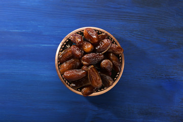 Bowl with dates on dark blue wooden background.