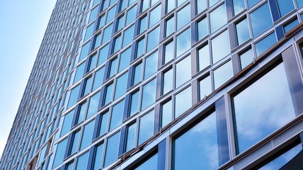Obraz premium Structural glass wall reflecting blue sky. Abstract modern architecture fragment. View of a modern glass skyscraper, modern office building. Modern office facade fragment with blue glass.