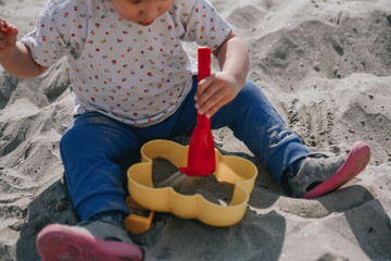 Little girl playing in the sand with boxes and sand shovel