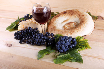 Wine, grape, cheese and bread on table