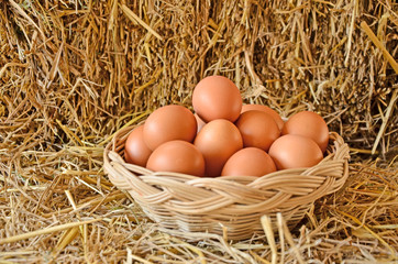 Woven rattan basket of eggs on straw floor