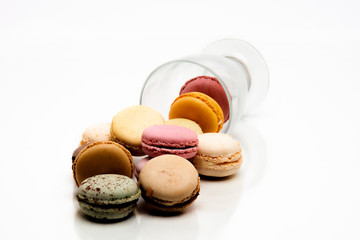 Macarons de couleurs sortant d'une coupe en verre sur fond blanc