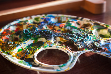 Dirty palette board. Bright acrylic paints close up. Drawing concept. Watercolor paints and brush. Artwork concept. Abstract colorful background. Hobby and homemade craft. Creative art.