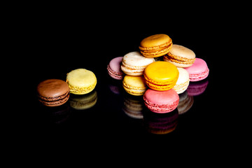 Ensemble de macarons multicolores sur fond noir avec reflets brillants