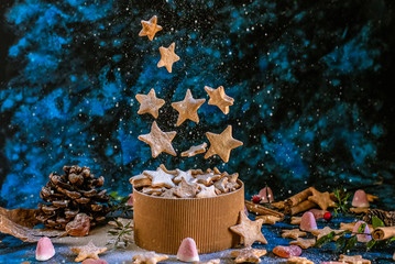Christmas cookies in the shape of stars that levitate in the air on a Christmas background with sweets and dried fruit
