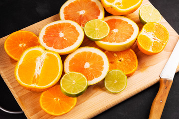 Sliced citrus fruits on a wooden board on a black background. Vitamin C is for your health